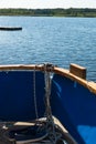 Close-up of a rope with a knotted end tied around a cleat on a wooden pier and shoes with anchors