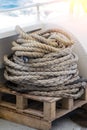 Close-up of a mooring rope with a knotted end tied around a cotter pin on a wooden pier. Nautical rope mooring