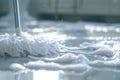 Close-up of a mop cleaning a soapy floor with bubbles and foam in a bright, clean environment. Royalty Free Stock Photo