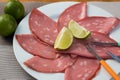 Close up of mortadella slices served with lemon on a white plate, on wooden background. top view Royalty Free Stock Photo