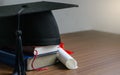 Close up mortar board and degree paper on wood table. Royalty Free Stock Photo