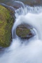 Close up of mossy rock with flowing water rushing downstream Royalty Free Stock Photo