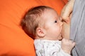 Close up mother breastfeeding her newborn child on a bed in a bright room. Royalty Free Stock Photo