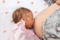 Close up mother breastfeeding her newborn child on a bed with a heart in a bright room. Mother breastfeeding her baby with breast Royalty Free Stock Photo