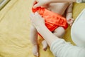 Close up of mother hands put on a baby orange diaper to her newborn Royalty Free Stock Photo