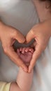 Close up mother holding hands newborn boy and giving heart signal in a room Royalty Free Stock Photo