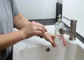 Close up of mothers hands cleaning a baby milk bottle with a brush, home kitchen sink Royalty Free Stock Photo