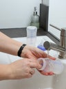 Close up of mothers hands cleaning a baby milk bottle with a brush, home kitchen sink Royalty Free Stock Photo