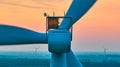 Close up of motor on wind turbine with orange sunset aerial of wind farm