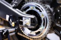 Close-up of the motorcycle wheel assembly, swingarm sprocket, and rear drive chain that powers the engine Royalty Free Stock Photo