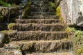 Close up of mountain stream flowing down stone steps in summertime. Manmade decorative waterfall flows down old stairs