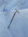 Close up of mountaineer\'s pike on glacier. Ice ax stuck in ice. Trekking, adventure and extreme nature