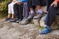 Close up of muddy shoes and trousers of a family sitting on stones by a lake, detail Royalty Free Stock Photo