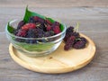 Close up of mulberry with a green leaves in Glass bowl on the wooden plate on wooden table. Mulberry this a fruit and can be eaten Royalty Free Stock Photo