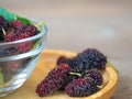 Close up of mulberry with a green leaves in Glass bowl on the wooden plate on wooden table. Mulberry this a fruit and can be eaten Royalty Free Stock Photo