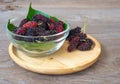 Close up of mulberry with a green leaves in Glass bowl on the wooden plate on wooden table. Mulberry this a fruit and can be eaten Royalty Free Stock Photo