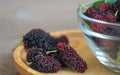 Close up of mulberry with a green leaves in Glass bowl on the wooden plate on wooden table. Mulberry this a fruit and can be eaten Royalty Free Stock Photo