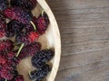 Close up of mulberry with a green leaves on the wooden plate on wooden table. Mulberry this a fruit and can be eaten in have a red Royalty Free Stock Photo
