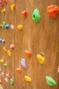 Close-up of multicolored hooks for rock climber on wooden wall in outdoor playground . Colorful abstract background