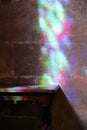 Multicolored reflections on the bare wall and on the old dark table