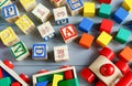 Close up Multicolored wooden cubes with letters, car, rainbow arc on gray background. Set of toys for studying alphabet. Education