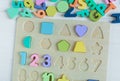 Close up Multicolored wooden letters, shape sorter board on white wooden background. Set of toys for studying alphabet. Education, Royalty Free Stock Photo