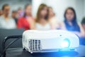 Close-up multimedia projector with blurred people background. Royalty Free Stock Photo