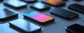 Close up of multiple black smartphones arranged on a table with colorful screen reflections Royalty Free Stock Photo