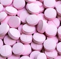 Close up of multiple round pink pills on black background