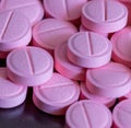 Close up of multiple round pink pills on black background