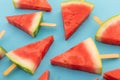 Close up of multiple watermelon triangles on wooden sticks on blue background