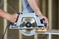 Close-up of muscular carpenter hands using new shiny modern powerful circular sharp electrical saw for cutting hard wooden board. Royalty Free Stock Photo