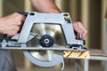 Close-up of muscular carpenter hands using new shiny modern powerful circular sharp electrical saw for cutting hard wooden board. Royalty Free Stock Photo