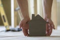 Close-up of muscular male hands holding small brown wooden model house on blurred background of building tools. Construction, inve Royalty Free Stock Photo