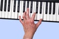 Close-up of a musical artist`s hand playing on a synthesizer keyboard. Blue background. Royalty Free Stock Photo