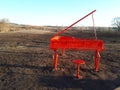 Close-up of a musical instrument, red piano against a dark field and blue sky