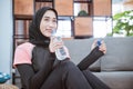 close up of muslim woman wearing a hijab gym outfit sits on the floor holding a drinking water bottle Royalty Free Stock Photo