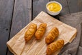 Close-up of mustered sauce on corn dogs over paper bag at wooden table