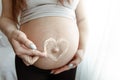 Close-up of a naked belly of a pregnant woman with a heart made of cream Royalty Free Stock Photo