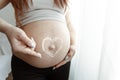 Close-up of a naked belly of a pregnant woman with a heart made of cream Royalty Free Stock Photo