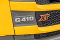 Close-up of the nameplate with the model name on the cab of the SCANIA G410 XT truck. Fragment of the yellow cab of the