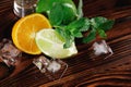 Close-up natural cocktail decorations. Juicy orange and healthy lime, ice cubes and mint leaves on a rustic background. Royalty Free Stock Photo