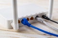 Close-up of network cables connected to a white Wi-Fi wireless router on a white wooden table. Wlan router with internet cables