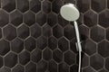 Close up of new rain shower head in the bathroom against a background of black tiles.