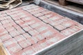 Close-up of new and red paver stones pile in pallet fixed with stretch wrap.