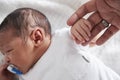 Close Up Of Newborn Baby In Cot Holding Parent`s Finger