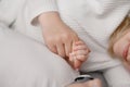 Close-up of newborn baby holding his mother hand with his fingers. Mom lies on bed next to infant, baby tightly holds Royalty Free Stock Photo