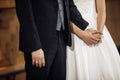 Close up newlywed couple, bride on wedding dress with lace and groom with tuxedo suit hold hand and standing together in Royalty Free Stock Photo