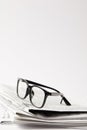 close up of newspapers with black eyeglasses, on white with copy space Royalty Free Stock Photo