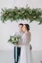 Close up of a nice young wedding couple. Wedding ceremony in light white room decorated with pine, flowers and candles.